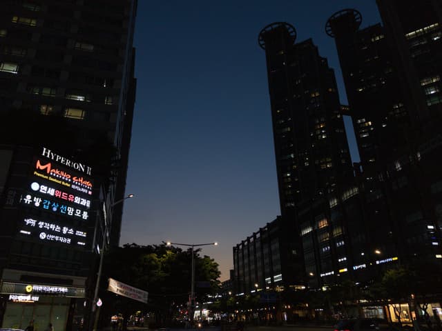 Urban street at dusk with high-rise buildings and illuminated LED signage