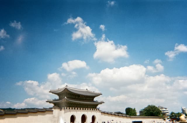 Traditional Korean palace gate with arched entrances under a blue sky with scattered clouds