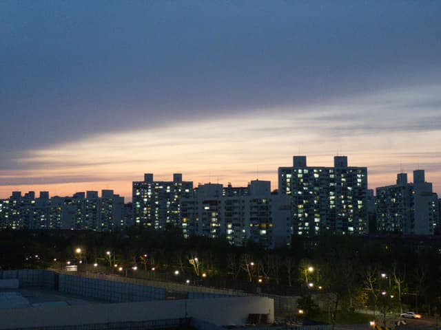 A cityscape at dusk with illuminated high-rise buildings against a colorful sky