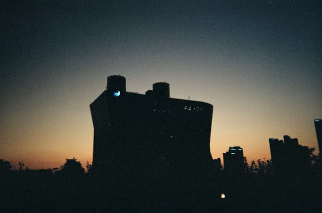 Dark building silhouette against an orange-blue dusk horizon with distant city outlines