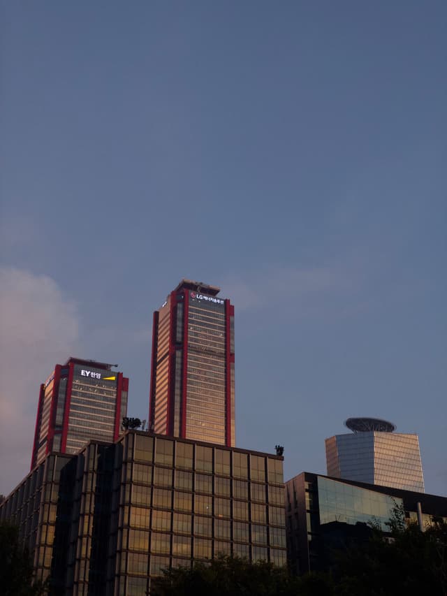 Tall modern buildings with reflective glass facades and red accents against a clear sky
