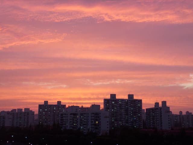 A city skyline silhouetted against a vibrant pink and orange sunset sky