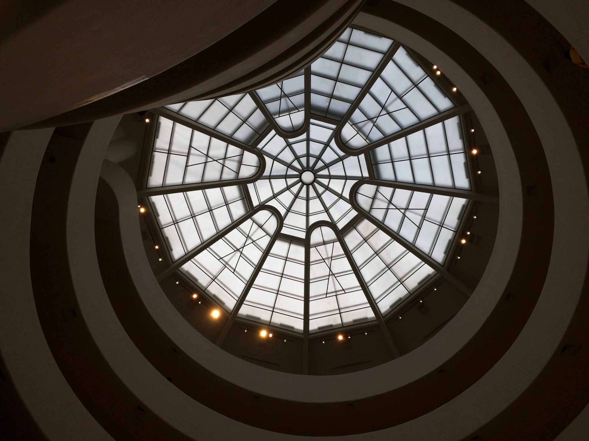 A view of a circular, glass-domed ceiling with concentric rings and a geometric pattern, seen from below
