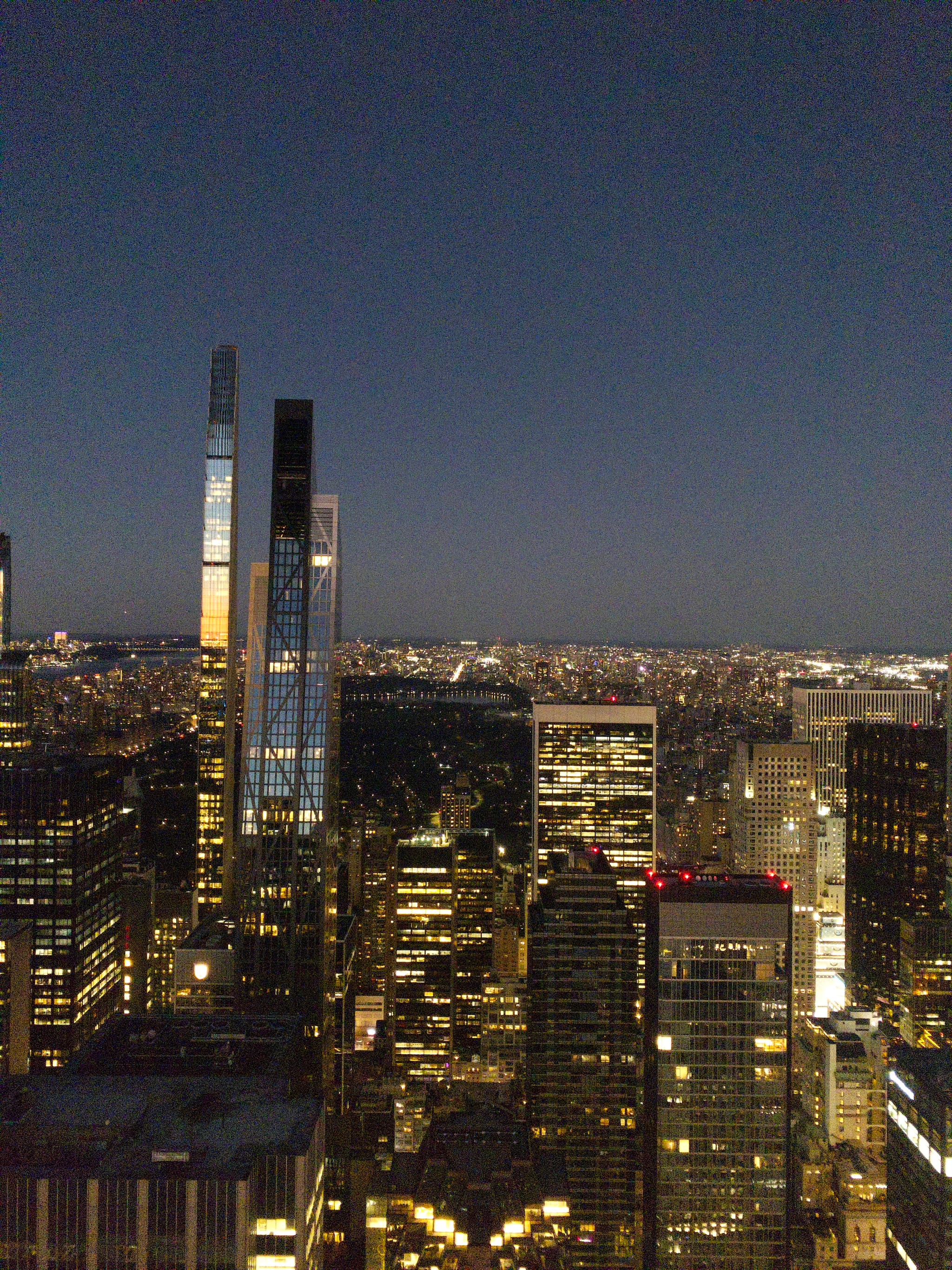 A nighttime cityscape featuring illuminated skyscrapers and a clear sky