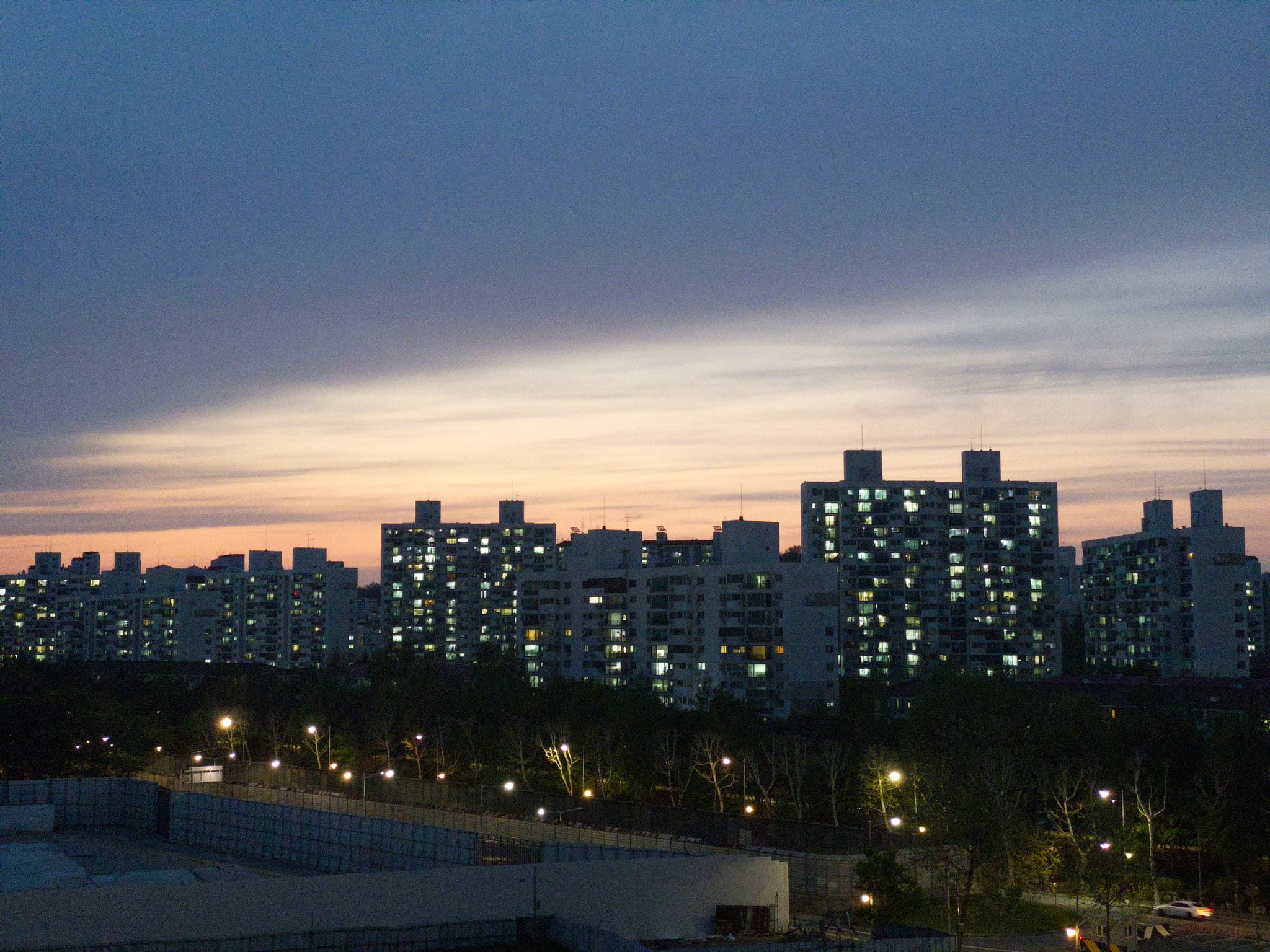 A cityscape at dusk with illuminated high-rise buildings against a colorful sky