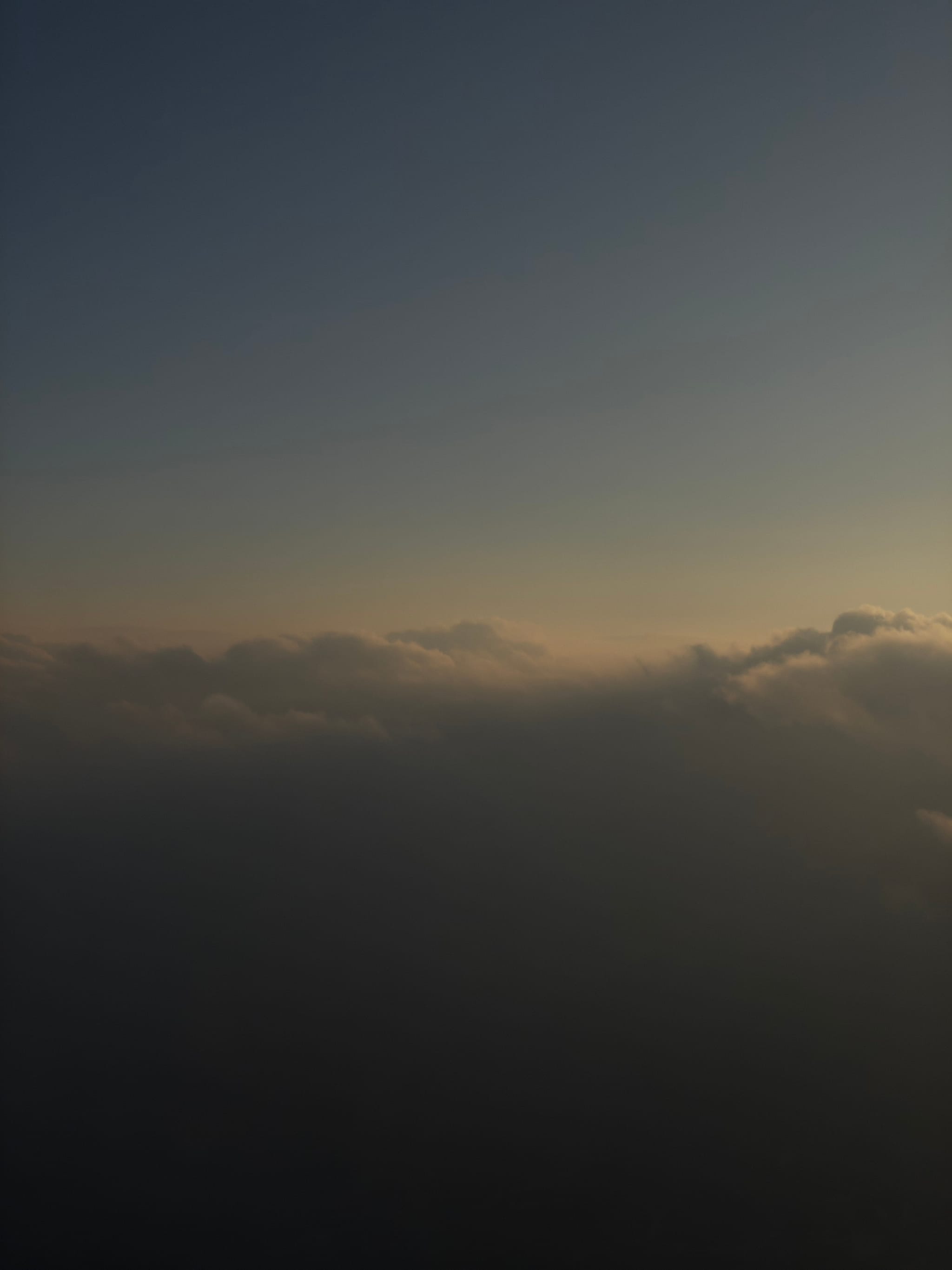 A serene view of clouds at sunset, with a gradient sky transitioning from deep blue to warm orange hues
