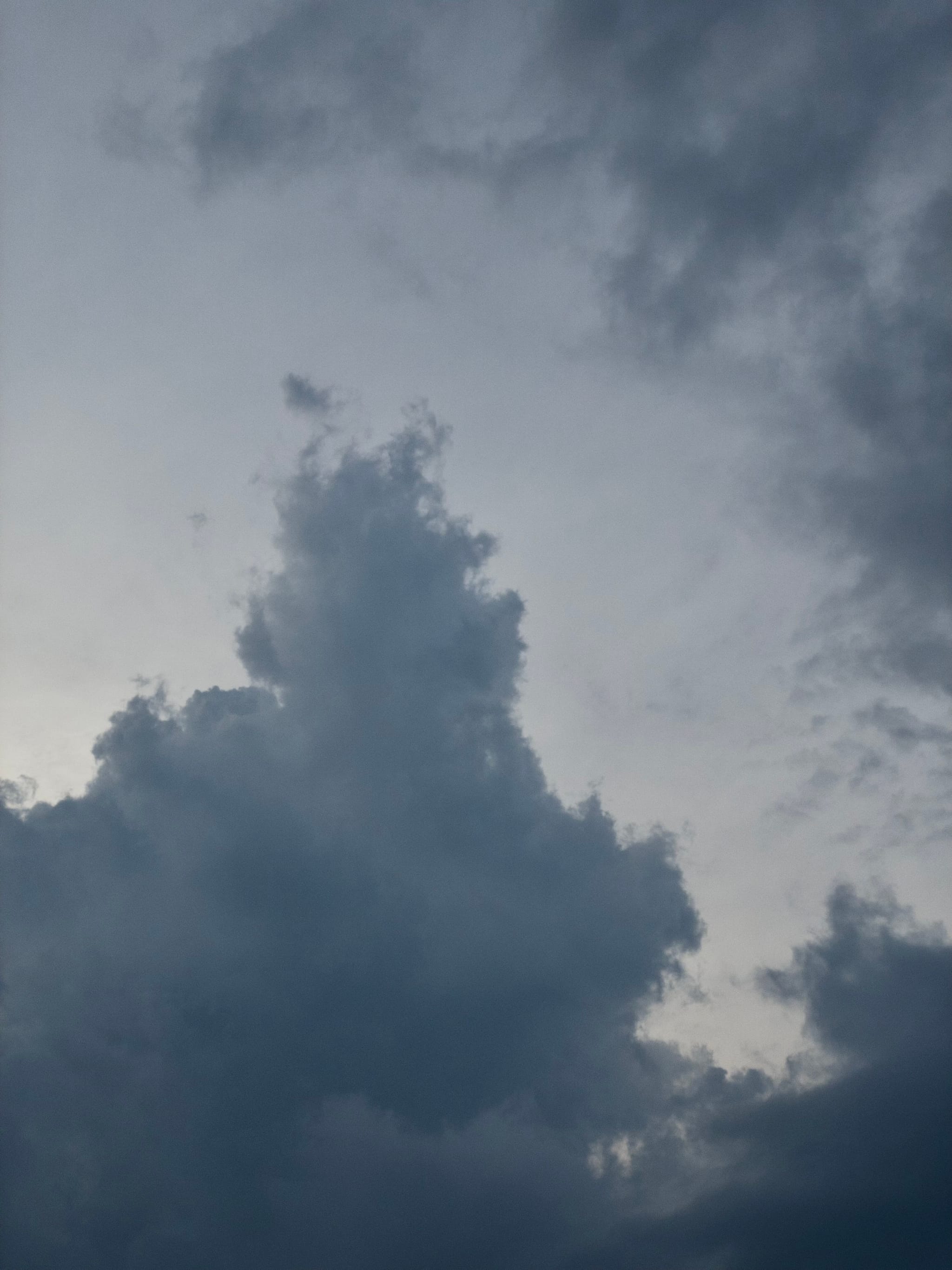 A cloudy sky with dark, billowing clouds against a dimly lit background