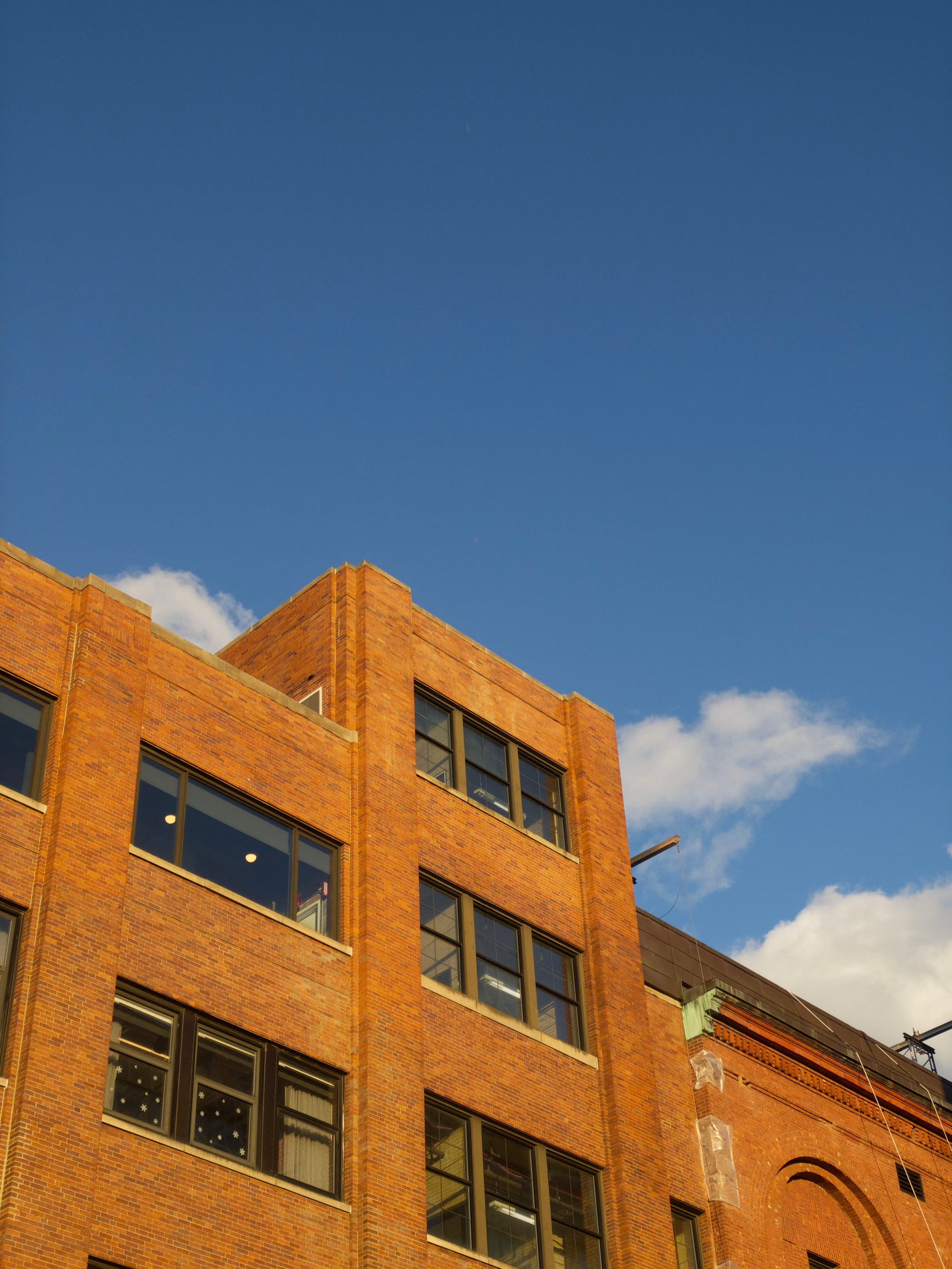 A brick building with multiple windows against a clear blue sky with a few clouds