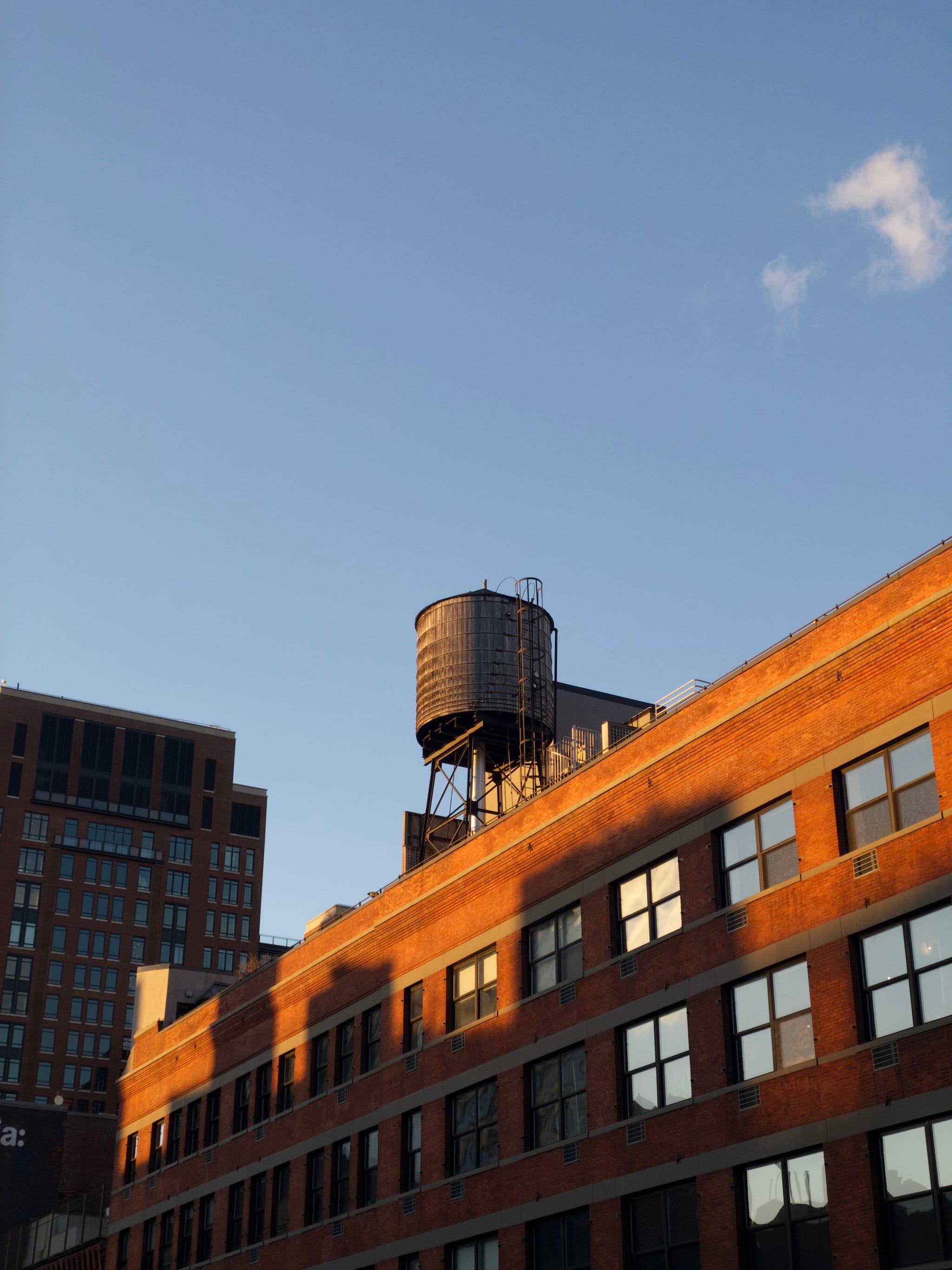 A rooftop water tower on a brick building against a clear blue sky