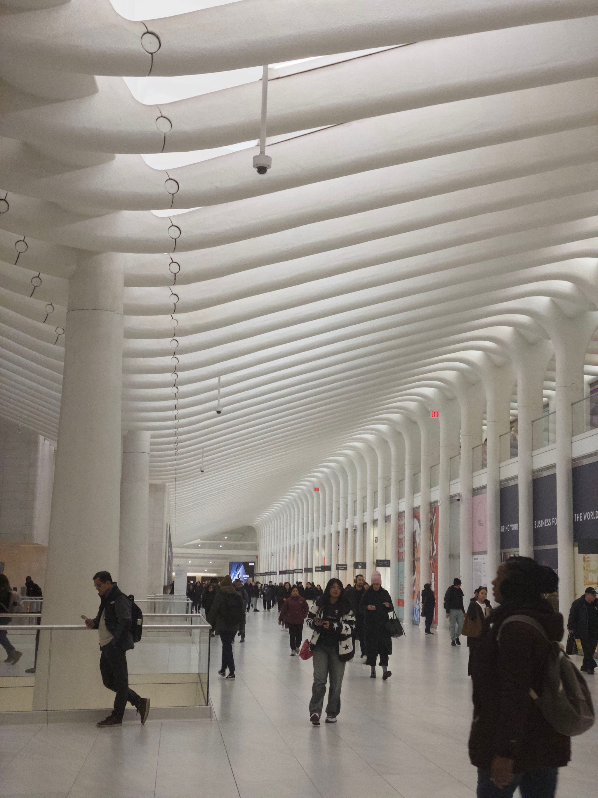 A spacious, modern interior with a high, ribbed ceiling and people walking through a corridor