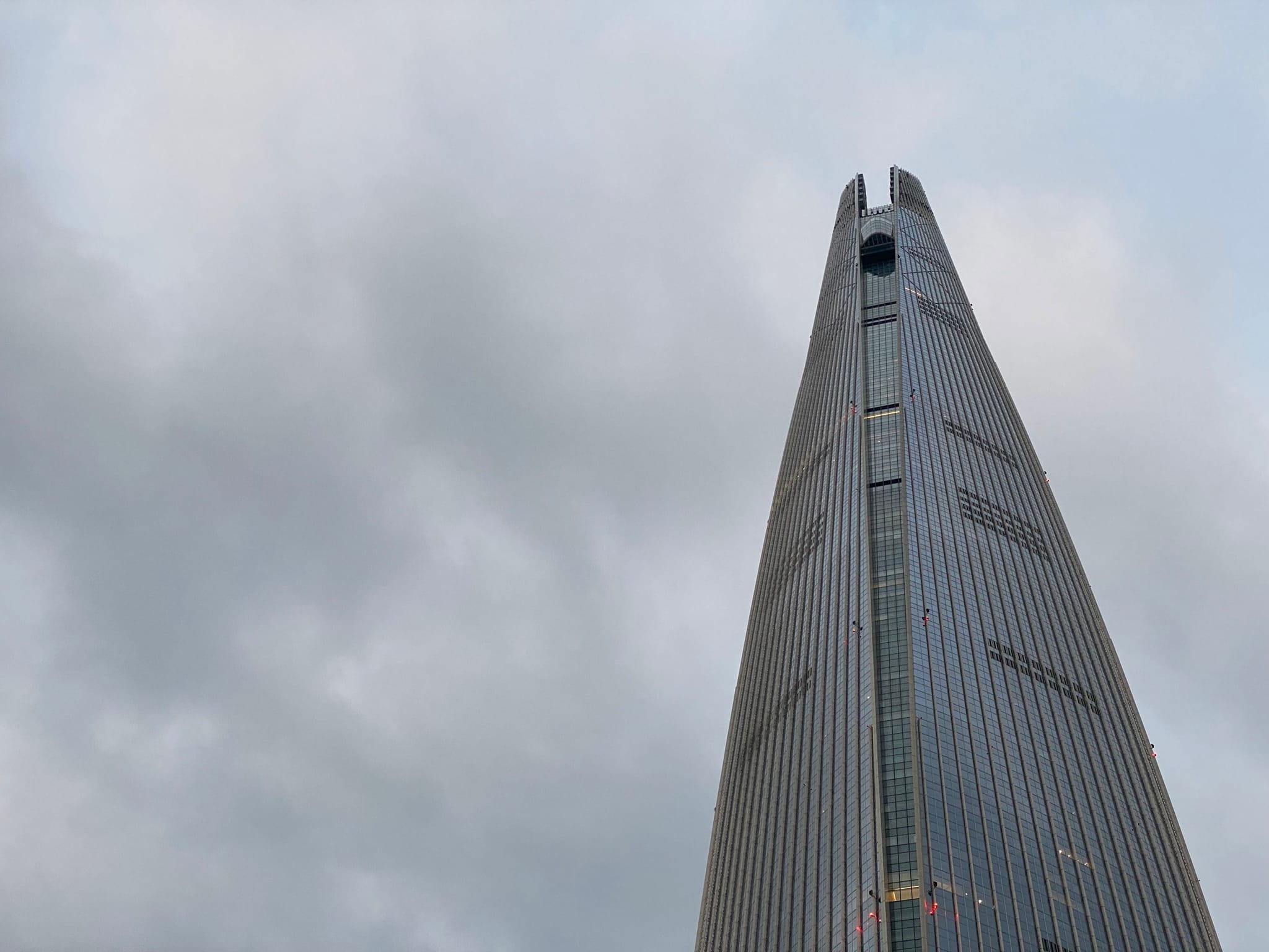 A tall, modern skyscraper with a sleek, pointed design against a cloudy sky