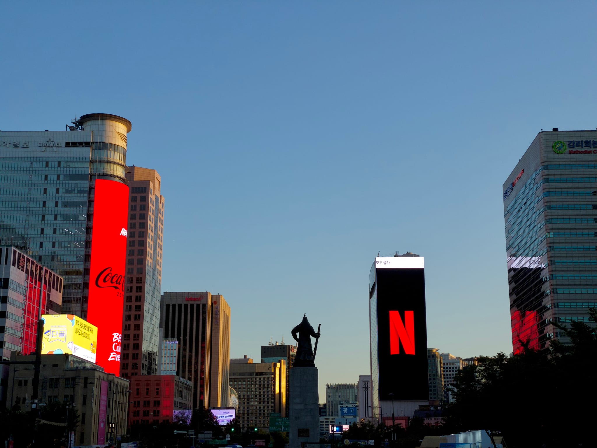 Skyscrapers with illuminated billboards against a clear evening sky