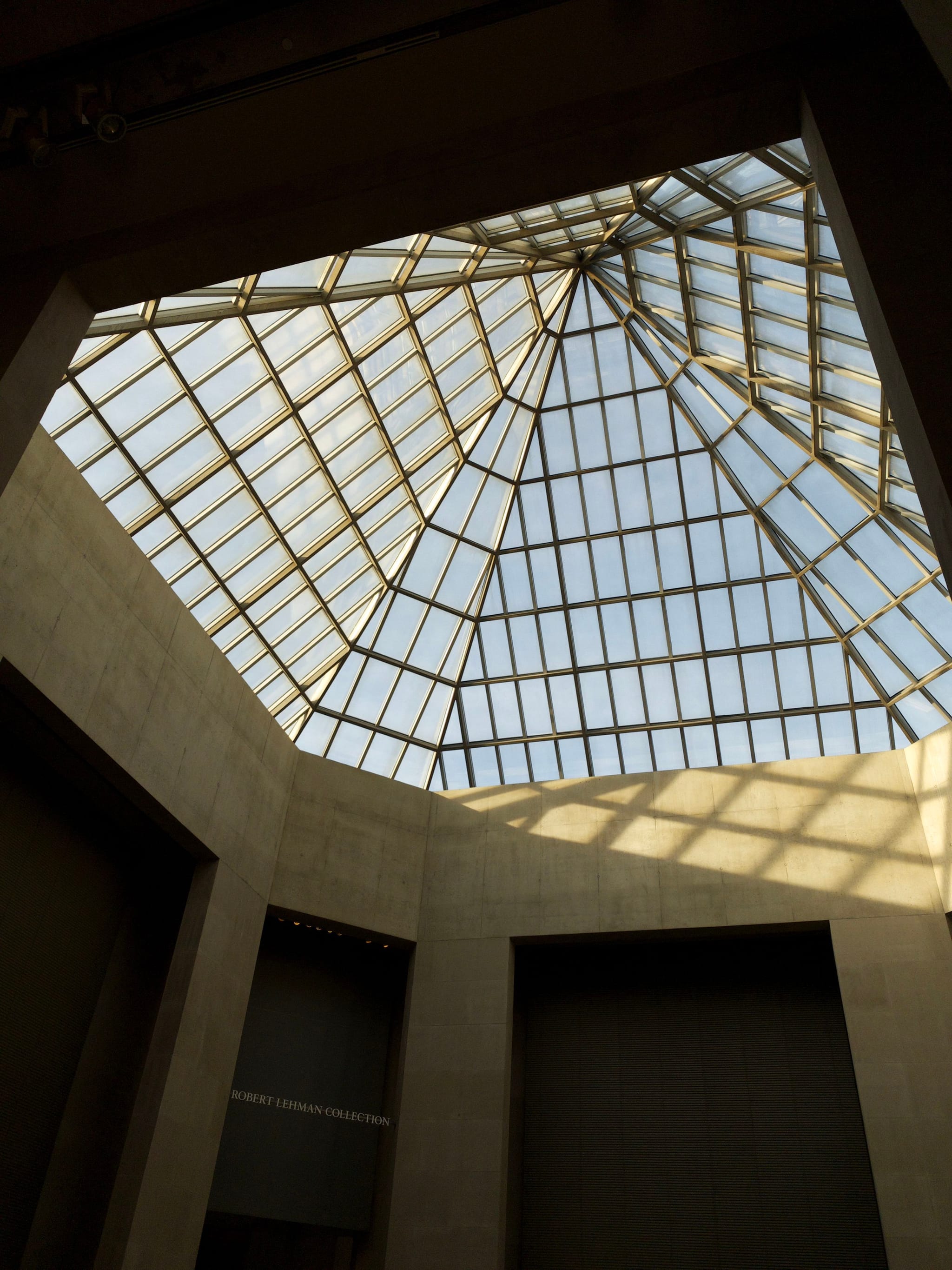 A geometric glass ceiling with a grid pattern, allowing natural light to illuminate the interior space below